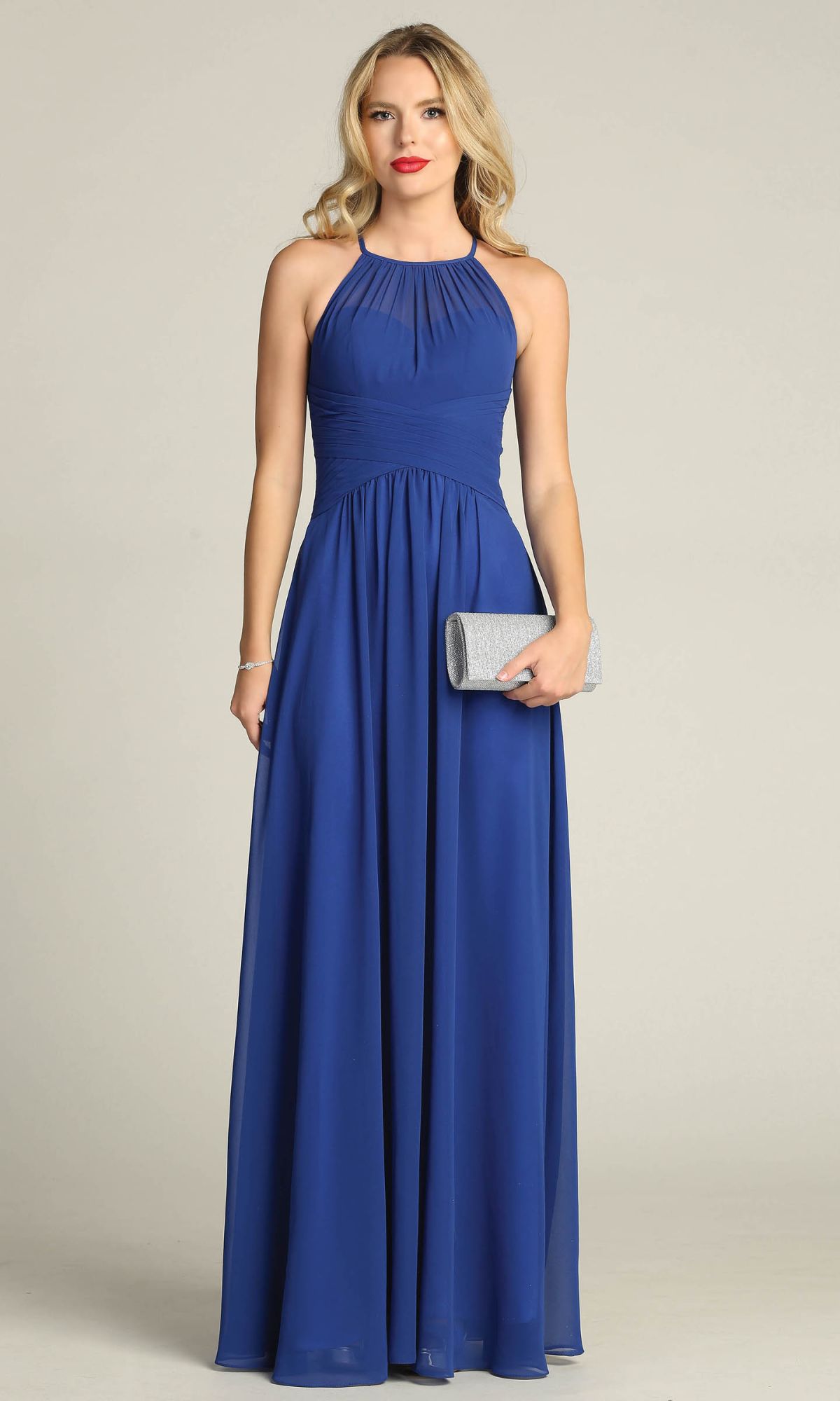 A woman wears the High-Neck Long A-Line Prom Dress: Chicas C5150, a sleeveless, floor-length royal blue plus-size gown, holding a silver clutch against a plain light background.